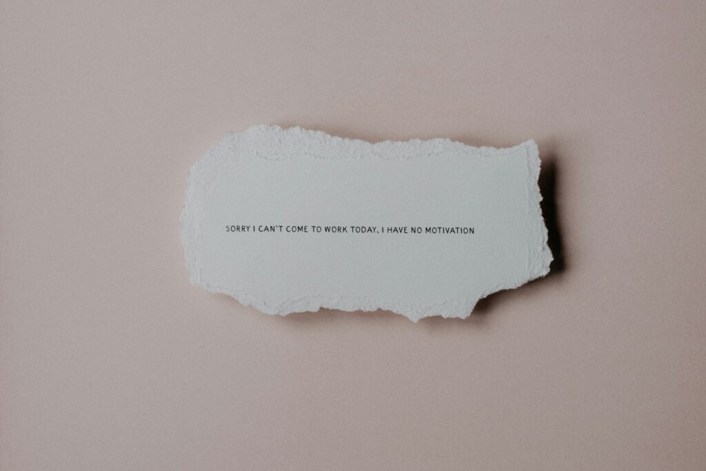 En tekst på et ark som sier "Sorry I can't come to work today, I have no motivation," perfekt for tilpassede klesbetegnelser og trykk.